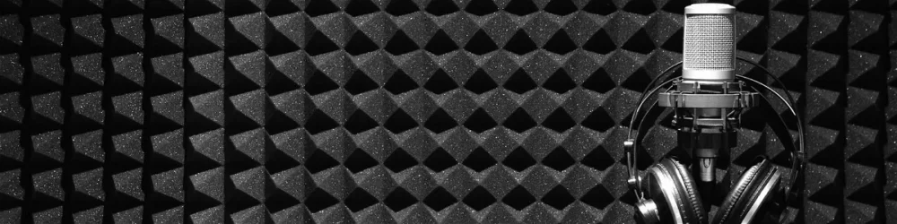 micrófono con unos auriculares colgados delante de una pared tratada acústicamente