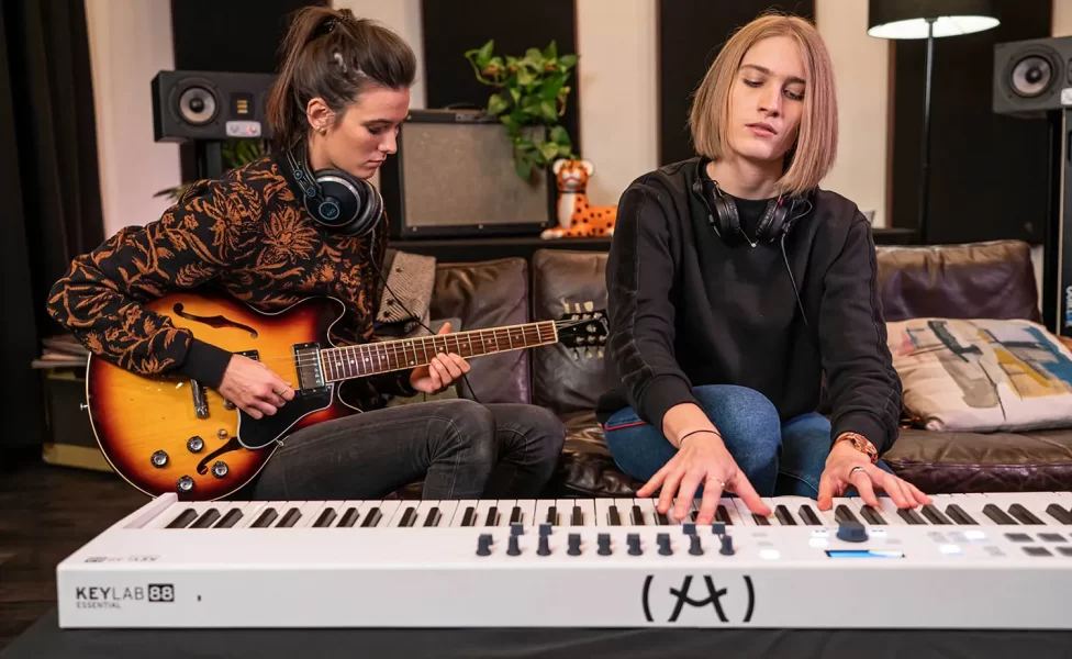 arturia keylab essential 88 tocado por una chica y otra chica con una guitarra
